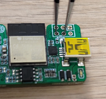 WiCAN USB opened: tweezers short the two pads of the header above the mini USB connector